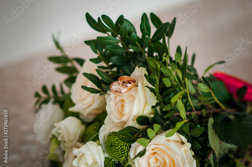 Bouquet of roses with golden wedding rings on it
