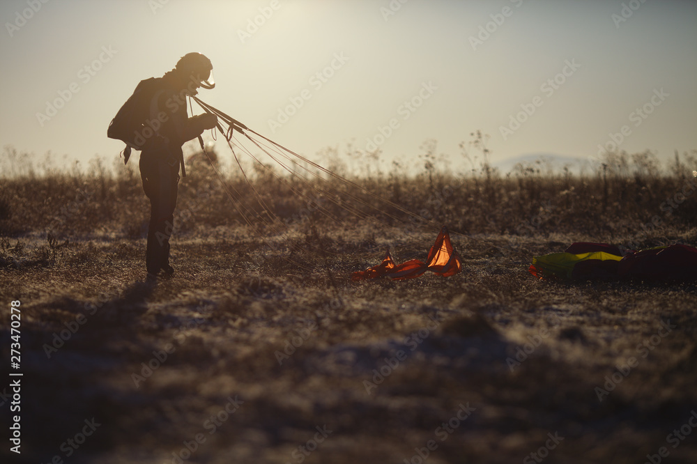Φωτογραφία Silhouette of a figure skydiver standing in the field after landing with a parachute