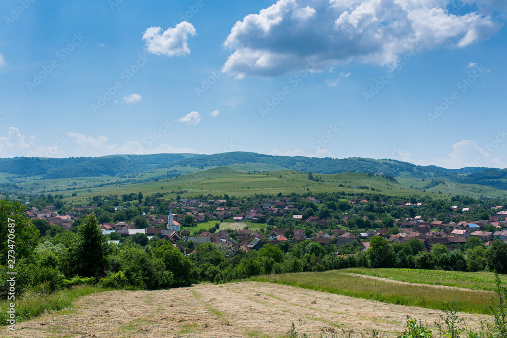 Small Transylvanian village at summertime , blue sky with white clouds in the background.