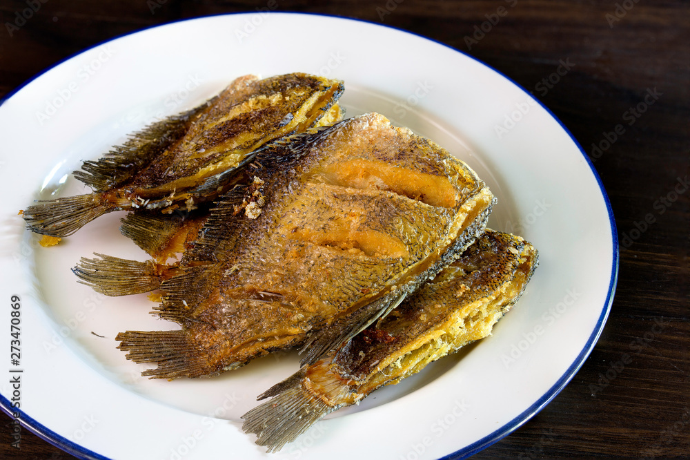 Fried dry salt fish (Thai language -pla salid) in white dish on dark background
