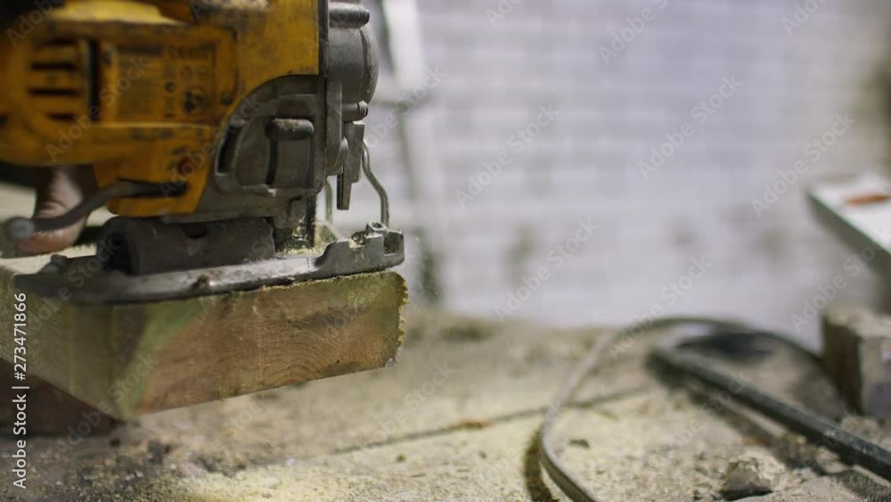 Workman cutting through a block of wood using a power tool Workman cutting through a block of wood using a power tool