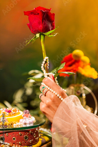 Cropped Hand holding Rose in front of Jewellery