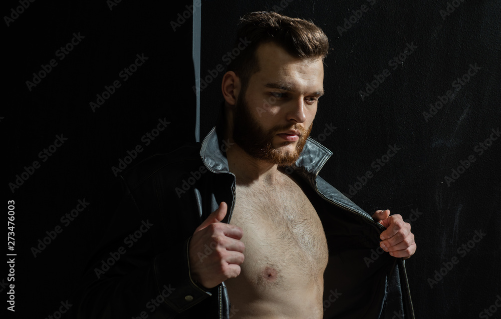 Portrait of handsome young man. Sexy fashion side half-faced view portrait  of a hot male model in stylish leather jacket with muscular body posing in  studio. Glamour photo. Beauty concept. foto de