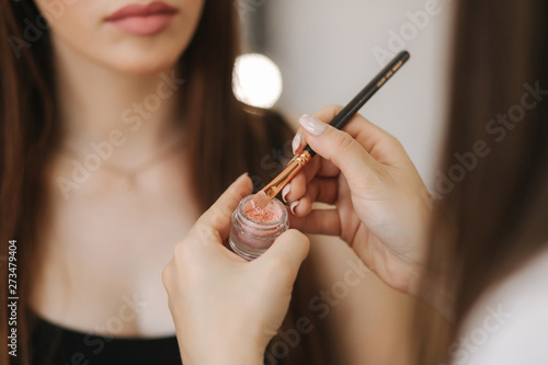 Makeup artist applies eye shadow  perfect evening makeup. Beauty redhead girl with perfect skin and freckles