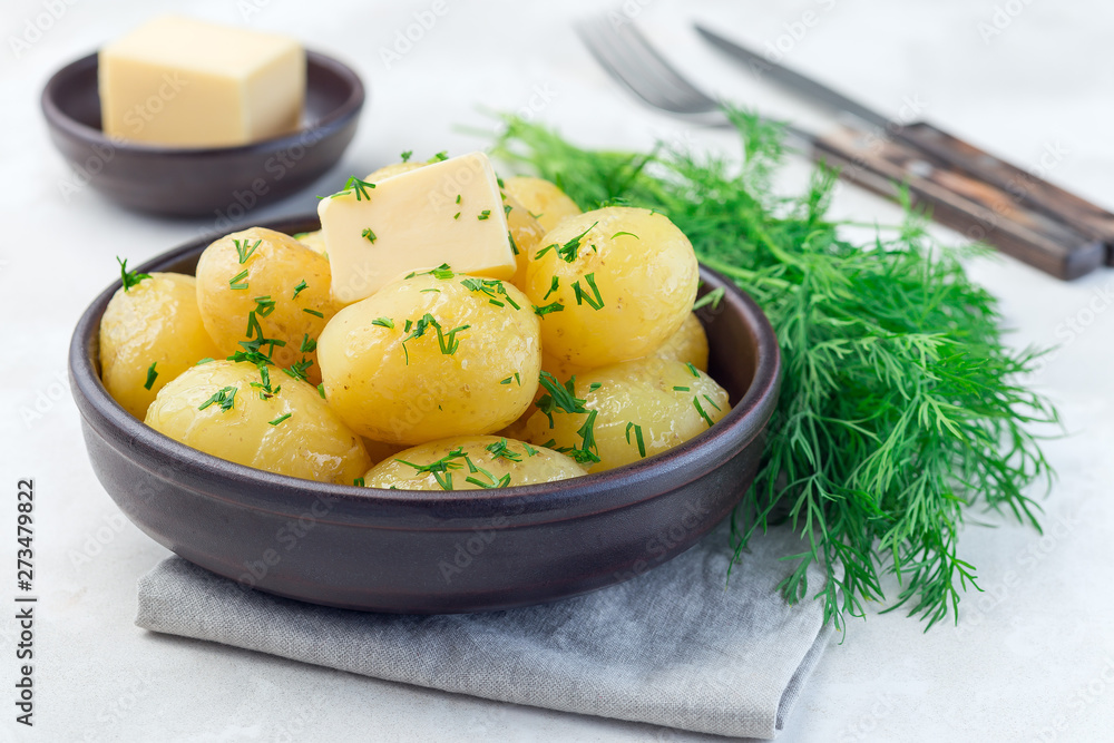 New young boiled potato topped with melted butter and chopped dill, in ceramic bowl, horizontal