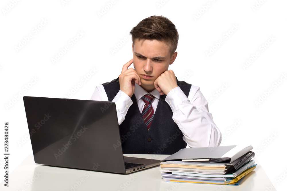 Young pensive businessman calculates taxes at desk in office. Isolated on white Young pensive businessman calculates taxes at desk in office. Isolated on white