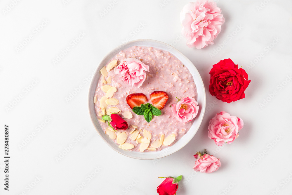 romantic healthy breakfast. bowl of overnight strawberry oats with fresh berries, almonds and mint with rose flowers romantic healthy breakfast. bowl of overnight strawberry oats with fresh berries, almonds and mint with rose flowers