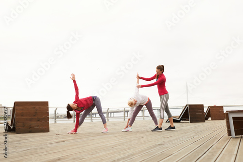 Wide angle portrait of senior women doing yoga outdoors during morning class on pier, copy space