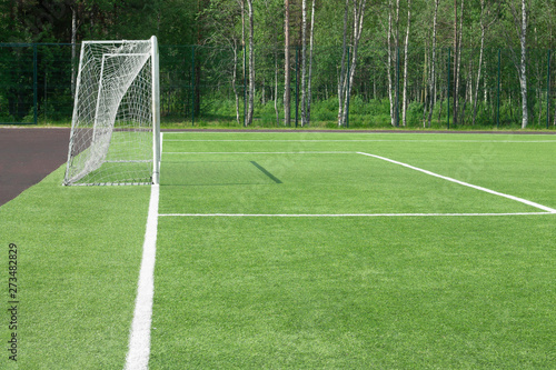 Football goal in the field. From which the shadow on a green grass falls. A look with a side.
