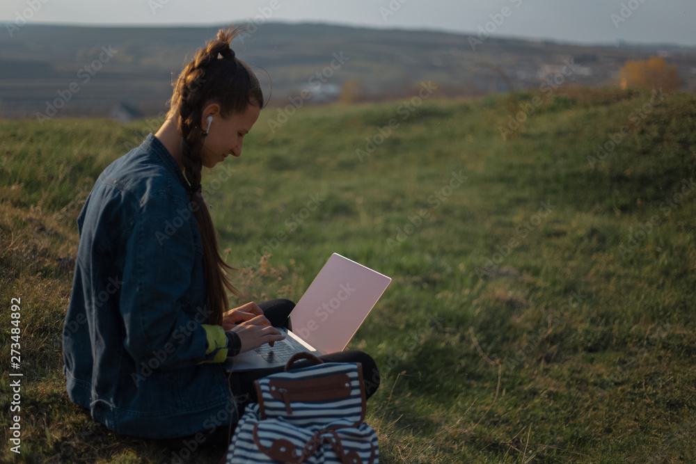 young girl working at laptop with earphones in the fields young girl working at laptop with earphones in the fields