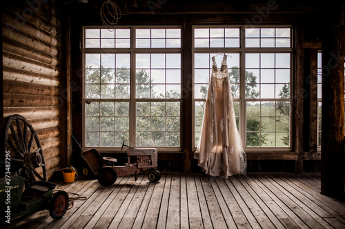 wedding dress hanging in rustic barn