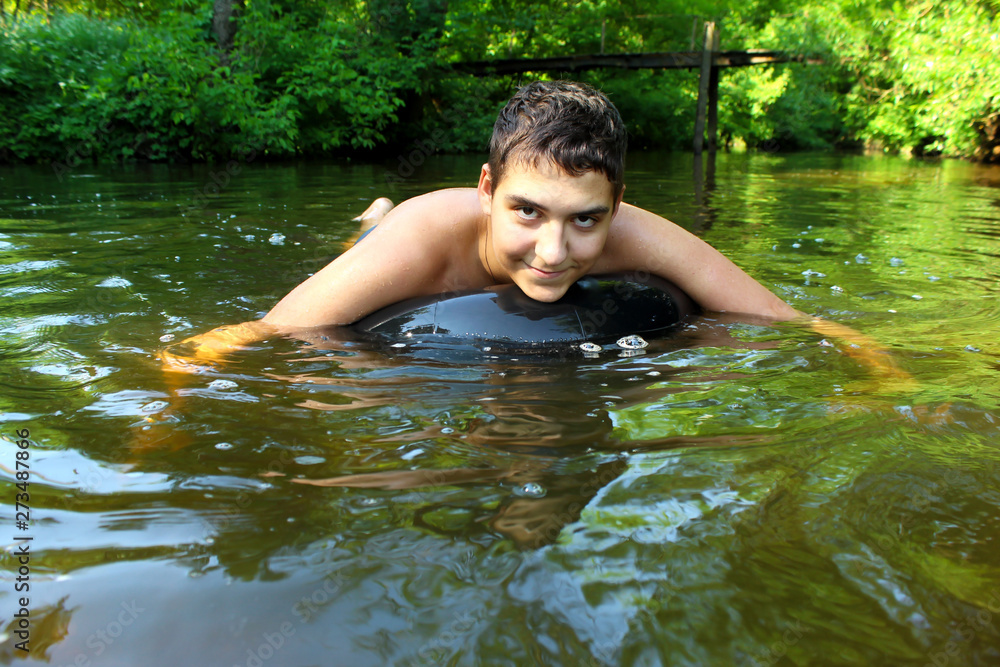 Fototapeta premium The boy has fun on an inflatable tubing in the river. 