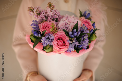 Fototapeta Naklejka Na Ścianę i Meble -  Girl holding a white spring box of tender pink and violet flowers