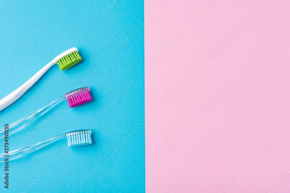 Three plastic toothbrushes on a colorful blue and pink background, close up Three plastic toothbrushes on a colorful blue and pink background, close up