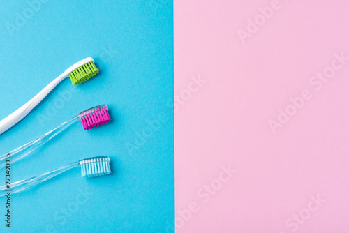 Three plastic toothbrushes on a colorful blue and pink  background  close up