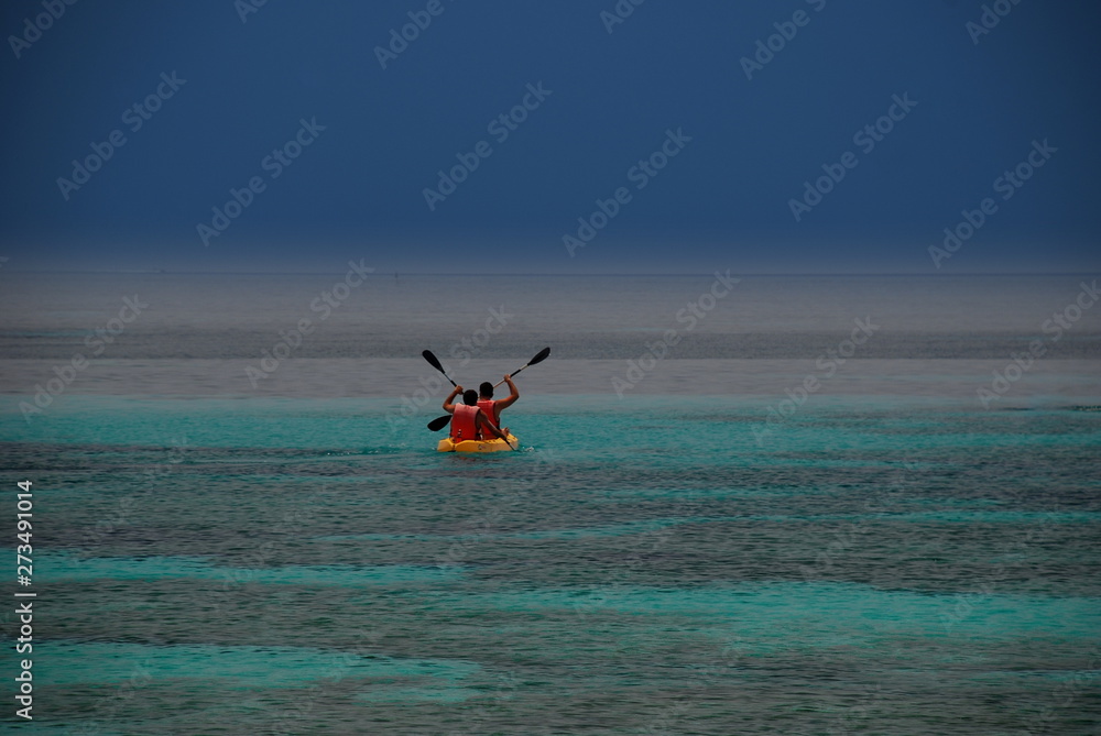Extraordinary image of two people rowing on a canoe on a sea of wonderful green and blue colors that stands out against a cobalt sky Extraordinary image of two people rowing on a canoe on a sea of wonderful green and blue colors that stands out against a cobalt sky