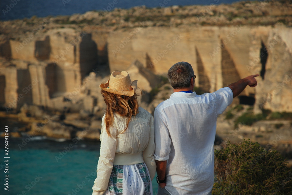 A young couple observes the extraordinary panorama of the Cala Rossa di Favignana at sunset