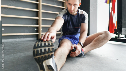 Portrait of a fitness man doing stretching exercises at gym
