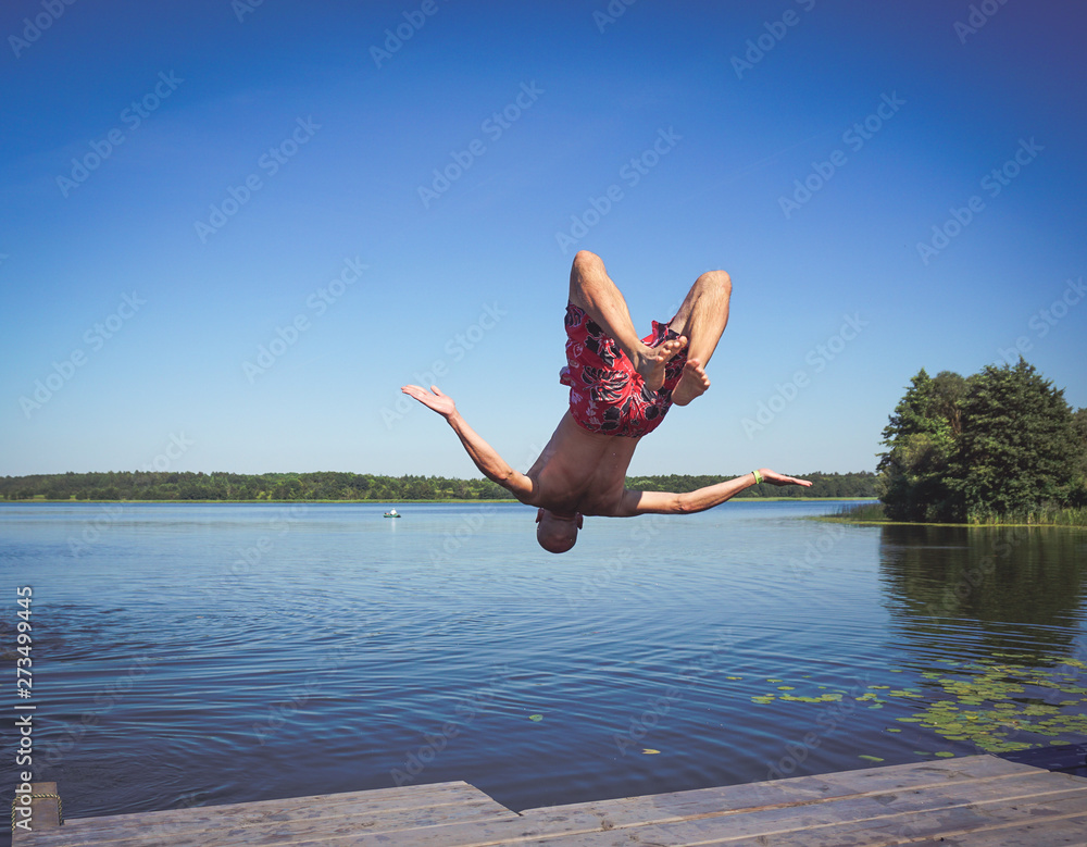 man jumps into the water of the lake, swims, enjoys spending time on summer holidays
