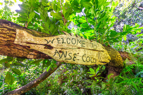 Welcome to Anse Coco sign in tropical jungle. Anse Cocos in La Digue Island, Seychelles is a popular beautiful beach can be reached with a trek starting from Grand Anse and passing through Petite Anse photo