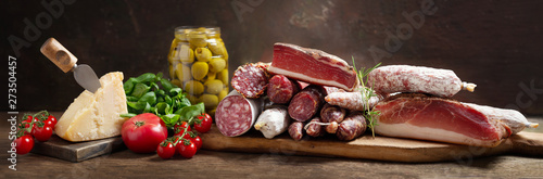 Italian food. Various kind types of salami, speck, sausages, parmesan cheese, olives, basil and fresh tomatoes