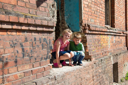 Brother and sister were left alone as a result of military conflicts and natural disasters. Children in a ruined and abandoned house. Staged photo.
