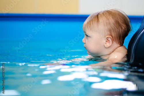 Cute sad baby boy learning to swim in special pool for little children © Lena May