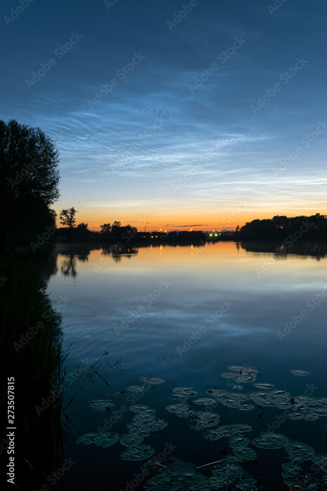 Silvery noctilucent clouds (night shining clouds) landscape over a dutch lake