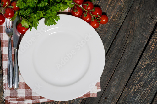 table setting with white plate and vegetables on wooden table
