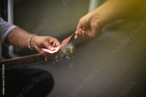 Beggars holding guitar are receiving money from people, Hands giving money and Hand holding receipt money - Image