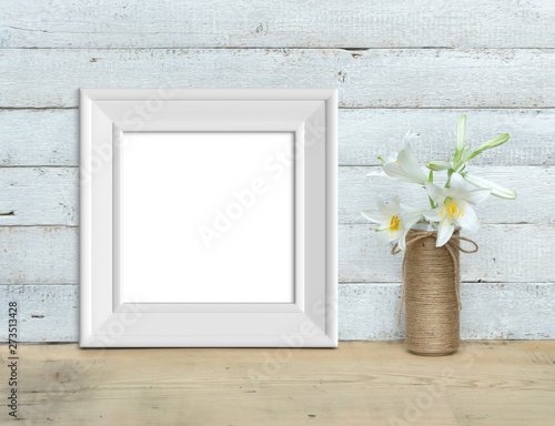 Square Vintage White Wooden Frame mockup near a bouquet of lilies stands on a wooden table on a painted white wooden background. Rustic style, simple beauty. 3d render.