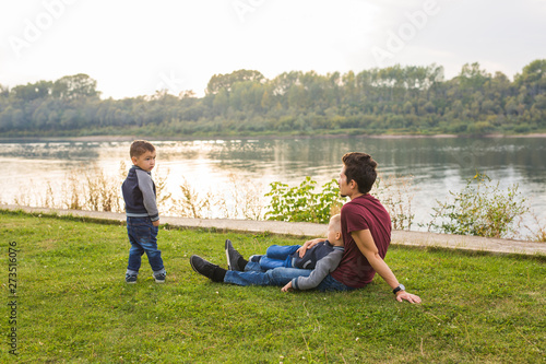 Childhood, family concept - father playing with son near the lake