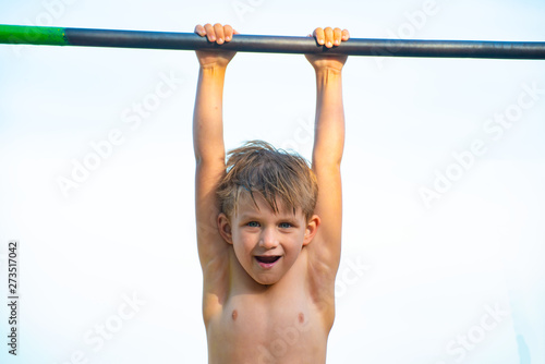 A little boy is hanging on the horizontal bar and can not do anything.