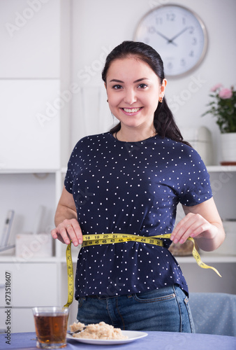 Smiling woman measuring waist photo