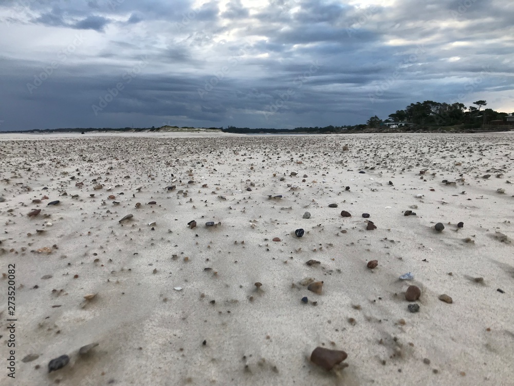 Storm clouds in Pinamar beach and sand with stones Storm clouds in Pinamar beach and sand with stones