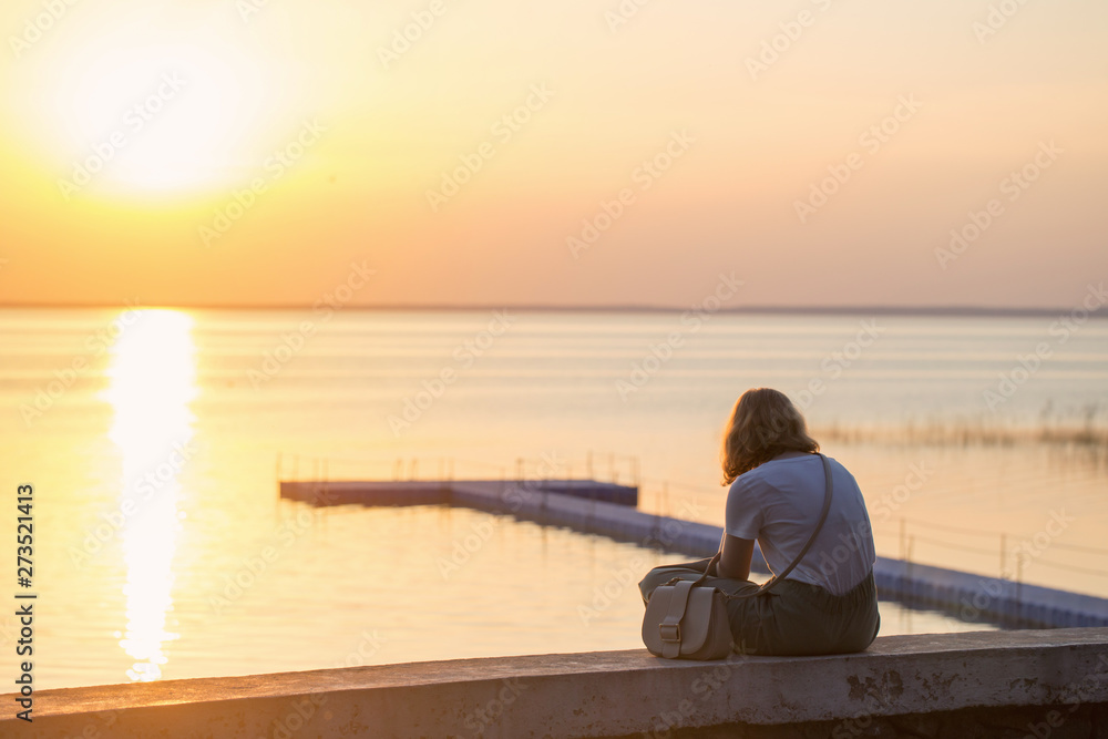 Fototapeta premium girl sitting on the promenade at sunset