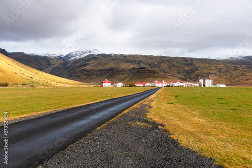 Empty back road to a farm at the foot of mountain in Iceland on a cloudy autumn day