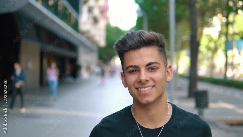 Closeup of young fashionable handsome man on the street of modern city. He is smiling and looks happy. New generation Closeup of young fashionable handsome man on the street of modern city. He is smiling and looks happy. New generation