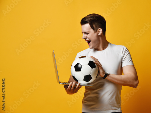 Young man with laptop and a soccer ball