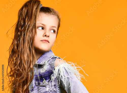Young teen girl model posing on a yellow background in jeans and a jacket.