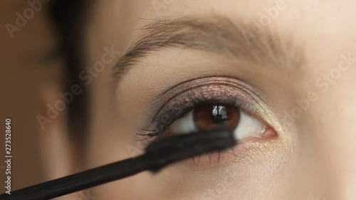 Closeup portrait of  woman applying mascara using  brush