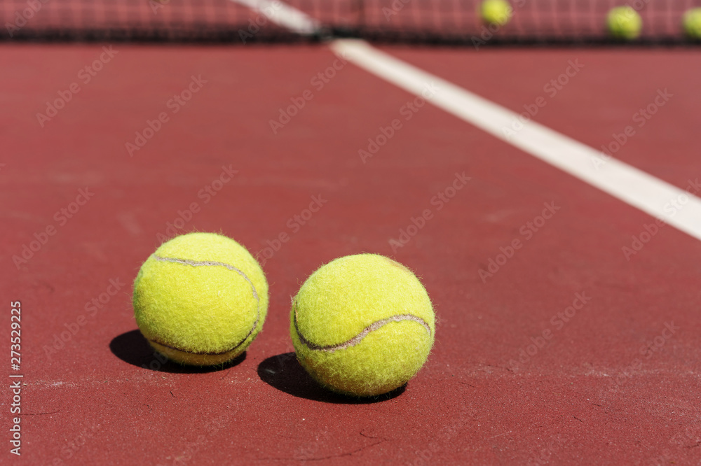 two yellow balls for playing tennis on clay outdoor court, concept of serving pitch in tennis