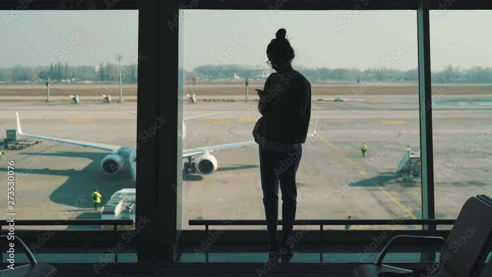 girl standing at the window in the airport terminal girl standing at the window in the airport terminal