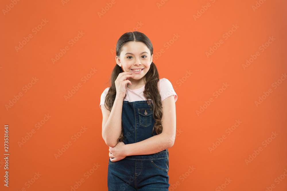 Nothing beats a great smile. Adorable little girl with big smile on orange background. Smiling child with white healthy smile on beautiful face. Cute small kid with long brunette hair and happy smile
