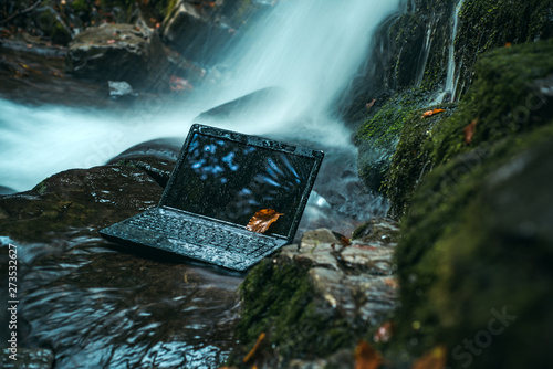 Obraz na plátně Laptop under the surface of the water on nature background