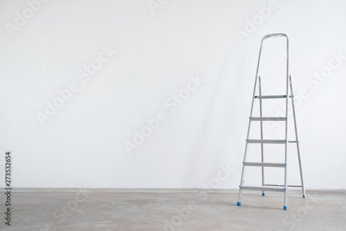 Ladder on a white wall background with copy space. Under construction concept background.