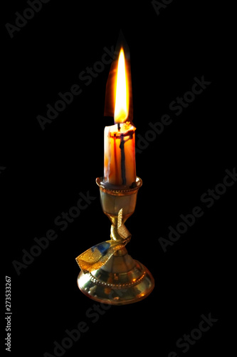 burning candle on an old candlestick on a black isolated background © Loryany