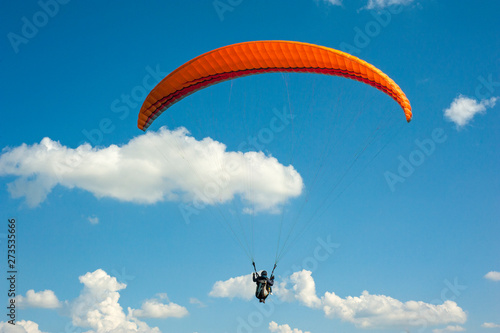 One paraglider is flying in the blue sky against the background of clouds. Paragliding in the sky on a sunny day. photo
