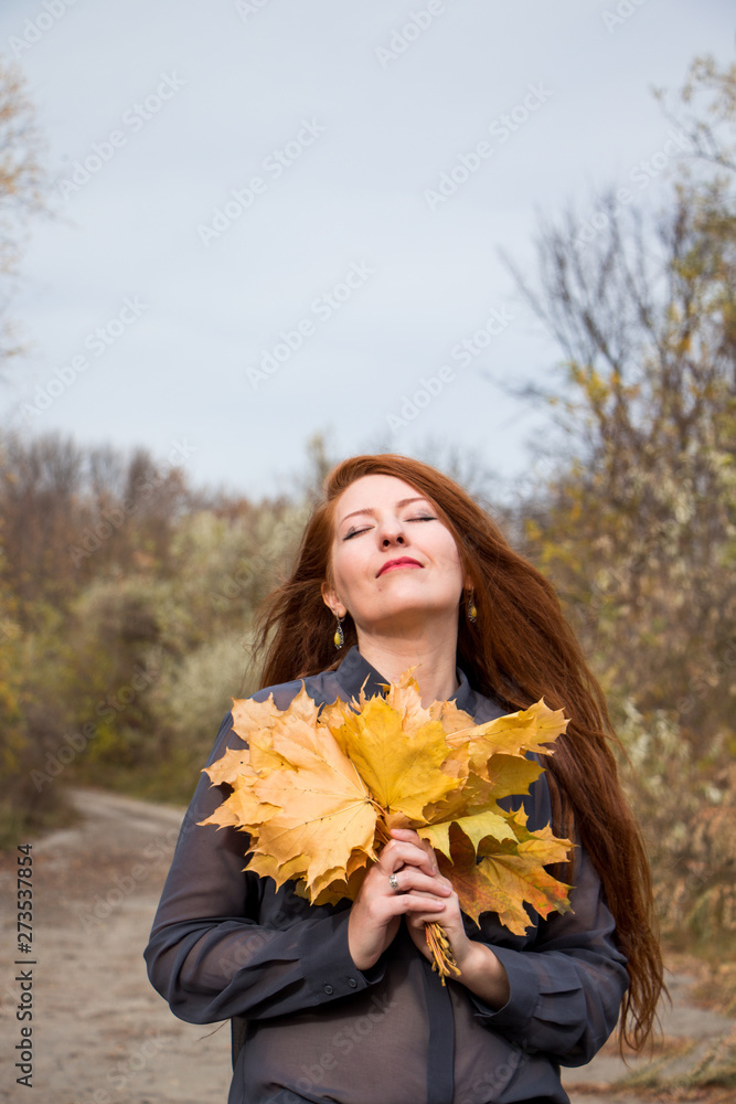 Portrait of young redhead woman with bouquet of yellow leaves Portrait of young redhead woman with bouquet of yellow leaves