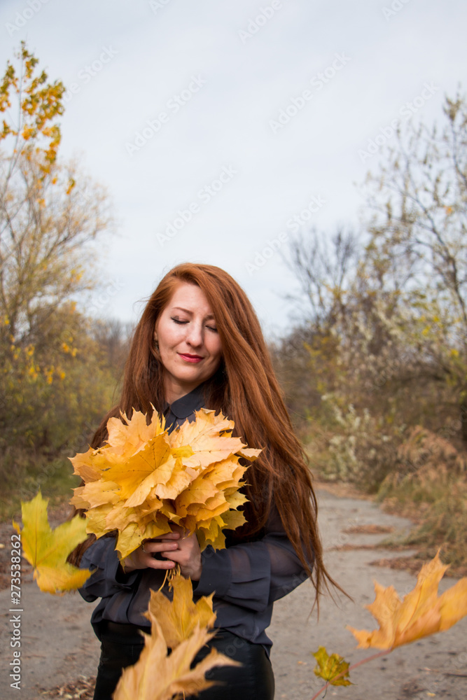Portrait of young redhead woman with bouquet of yellow leaves Portrait of young redhead woman with bouquet of yellow leaves